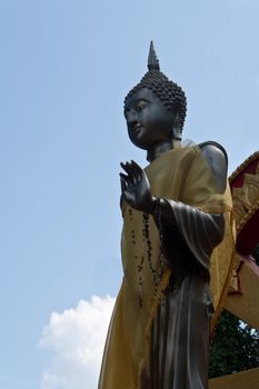 Black Buddha. In standing behind a blue sky.