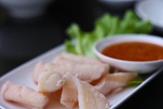 Poached fish on a dish with white sauce and green vegetables.