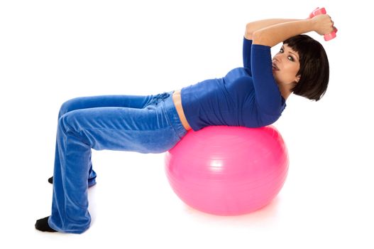 Instructor taking exercise class using ball and dumbbells at gym