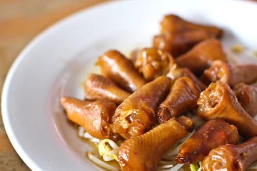 Stewed chicken leg with bean sprouts on a white plate.