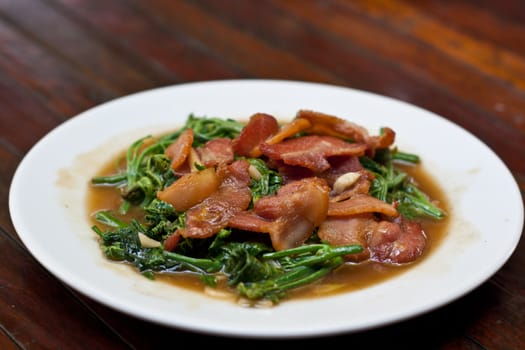 stir-fried chayote vegetables with bacon on whith dish.