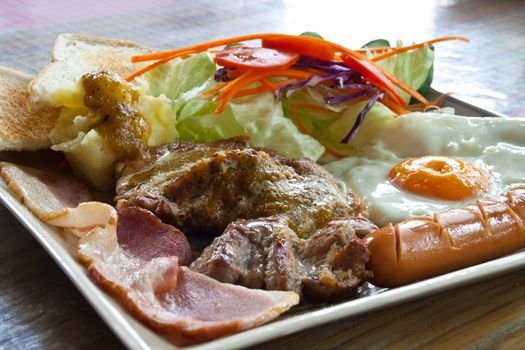 Steak pork, bacon, fried egg, sausage, bread and salad.