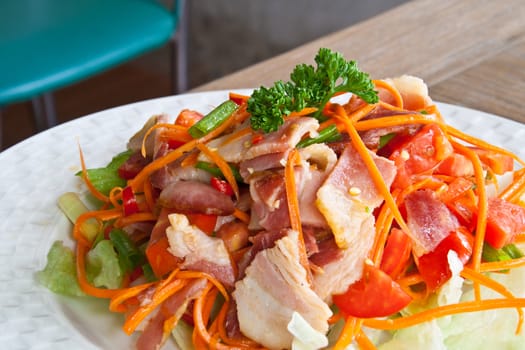 Spicy bacon salad with tomato carrot on white dish.