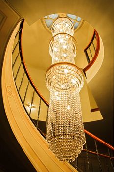 Generic portrait of a long crystal chandelier lighting up a stairwell of a spiral staircase. Location of this shot was Istanbul, Turkey