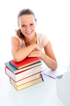 Smiling confident young college student seated at her desk with a pile of textbooks for her studies 