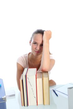 Despondent attractive young teenage scholar leaning on her elbow on top of her textbooks 