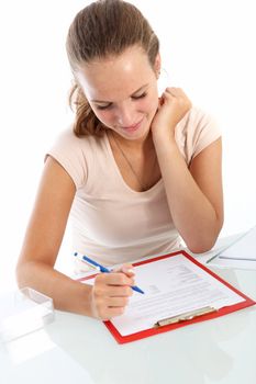 Attractive young female student smiling as she sits at a table with a clipboard reading through her exam questions 
