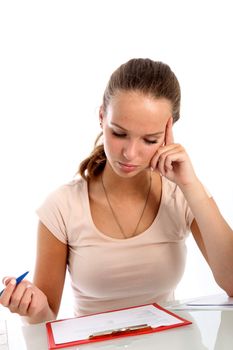 Female student seated at a table reading test questions clipped to a clipboard with a serious thoughtful expression 