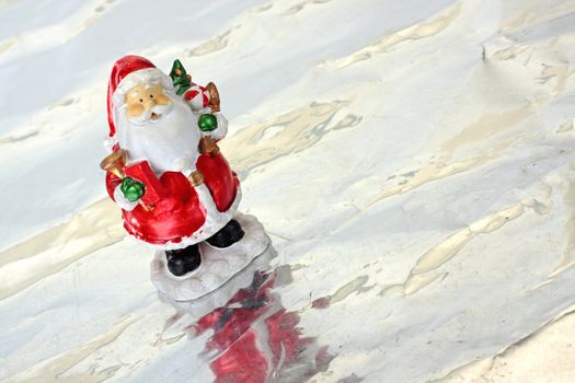 Toy Santa Claus on ice with christmas tree in hands