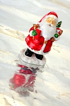 Toy Santa Claus on ice with christmas tree in hands