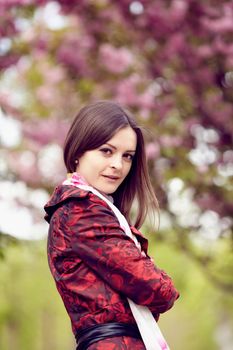 Beautiful girl in a red cloak against Sakura.