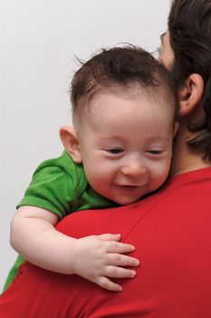 Rear view of cute smiling baby boy  looking over mother  shoulder