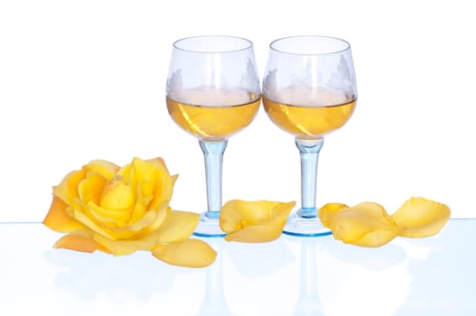 two tumblers with white wine and yellow rose on the party