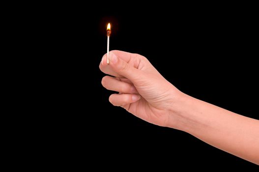 Woman holding burn match on black background