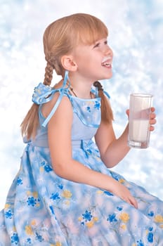 laughing girl drinking a glass of milk on blue background