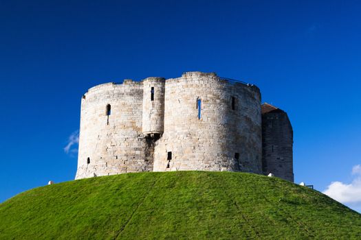 Medieval landmark architecture of cliffords tower in the centre of the historic city of york england under a clear blue sky