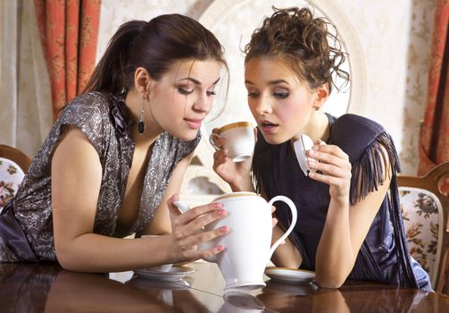 Two girlfriends have already drunk tea and look in an empty teapot