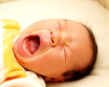 Newborn baby, yawning in it's own bed