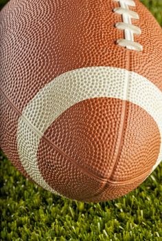 Strict close up of a football over green grass