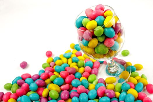 Color candie beans in glass on white background