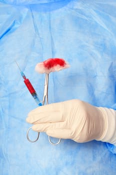 syringe and clamp with swab in the hand of the surgeon during a surgery