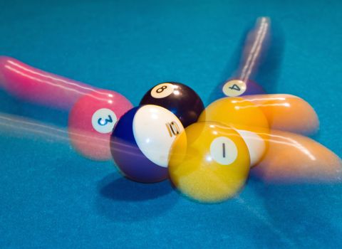 Billiards balls with motion on a green pool table