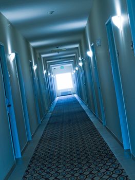 Empty, crooked hotel corridor in blue color tone
