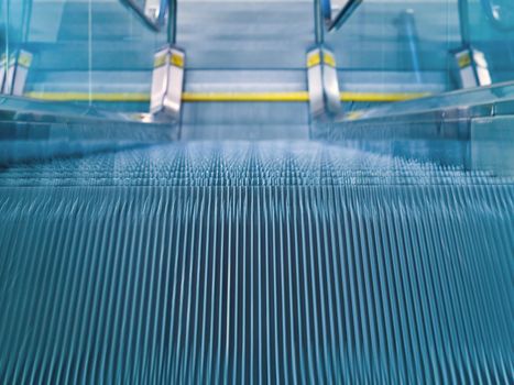An airport escalator from the top landing showing motion blur