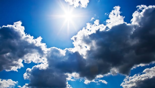 Bright sunrays in a blue cloudy sky
