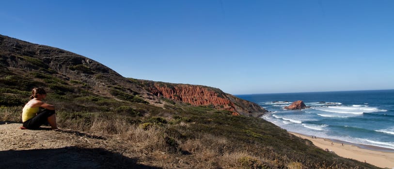 View of a young woman watching a beautiful landscape on the Sagres region.