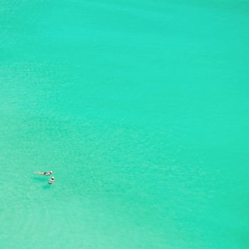 Two persons are swimming in the clear sea