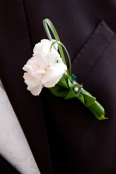 White small decoration flowers on man's black wedding suit