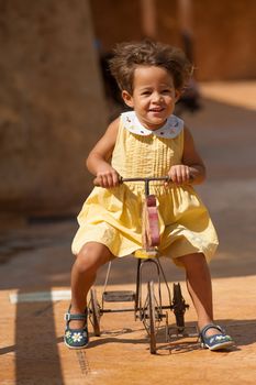 Happy girl riding a centenarian toy tricycle