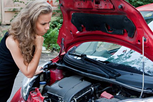 Beautiful young woman near the broken car