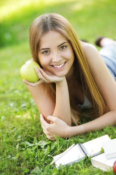 Young smiling woman outdoors holding an apple