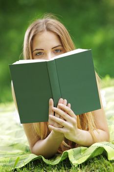 Young woman on a grass looking over the book