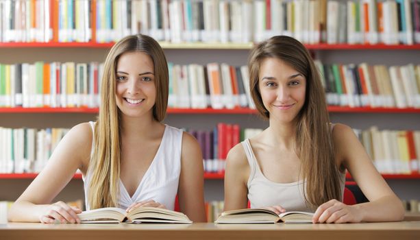 Two female students looking smiling at the library
