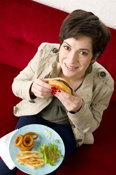 A beautiful woman begins to eat a burger