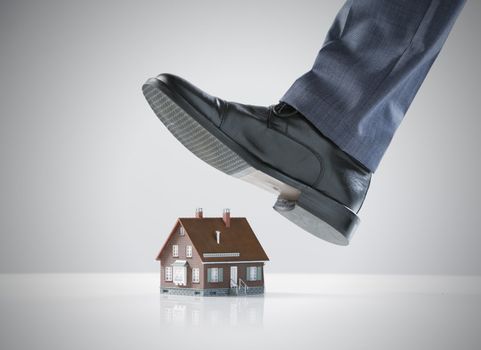 Businessman foot about to crush a small house