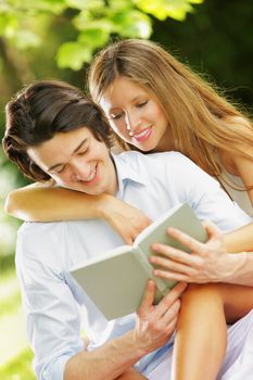 a young couple read a book together in the park. close up.