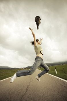 Young woman jumping  on the long empty street.