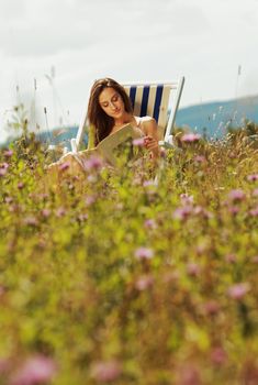 Young woman reading a book in a flowers field