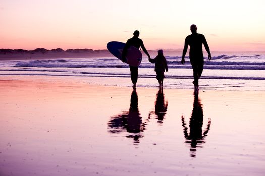 Female surfer and her familly walking in the beach at the sunset