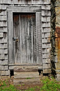 An old wooden door beside a chimney on the back of a house.
