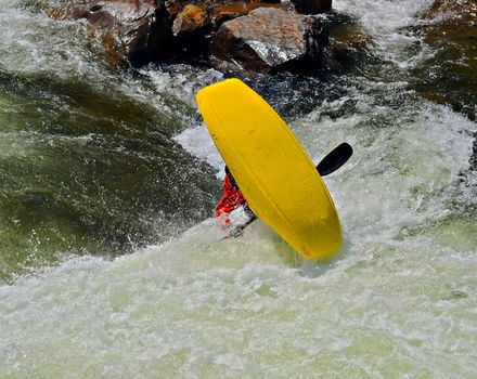 A man in the river rolling upside down in his kayak.