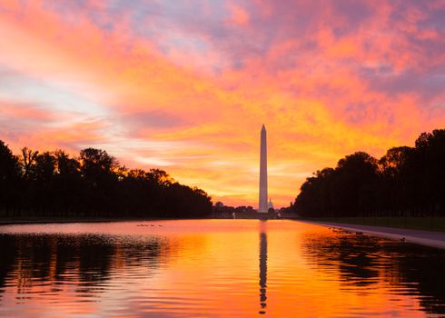 Bright red and orange sunrise at dawn reflects Washington Monument in new reflecting pool by Lincoln Memorial