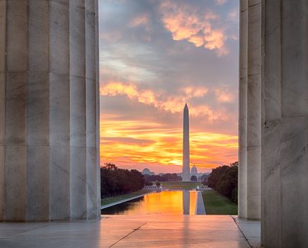 Bright red and orange sunrise at dawn reflects Washington Monument in new reflecting pool by Lincoln Memorial