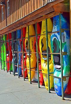 Kayaks on the side of an outdoor center building waiting to be rented.