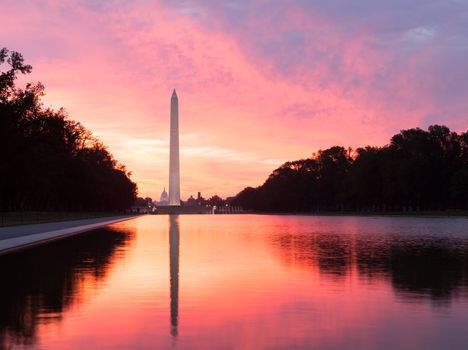 Bright red and orange sunrise at dawn reflects Washington Monument in new reflecting pool by Lincoln Memorial