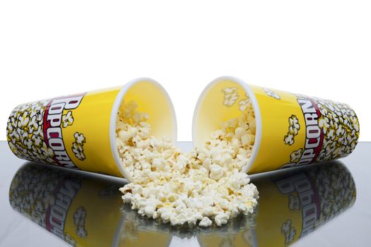 two cups of spilled popcorn with white background